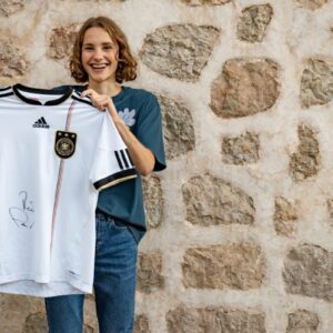 Food-Influencerin Maya Leinenbach (@fitgreenmind) mit dem signierten Trikot ihres Idols René Adler.
© Story House Prod. GmbH / Duncan Kendall